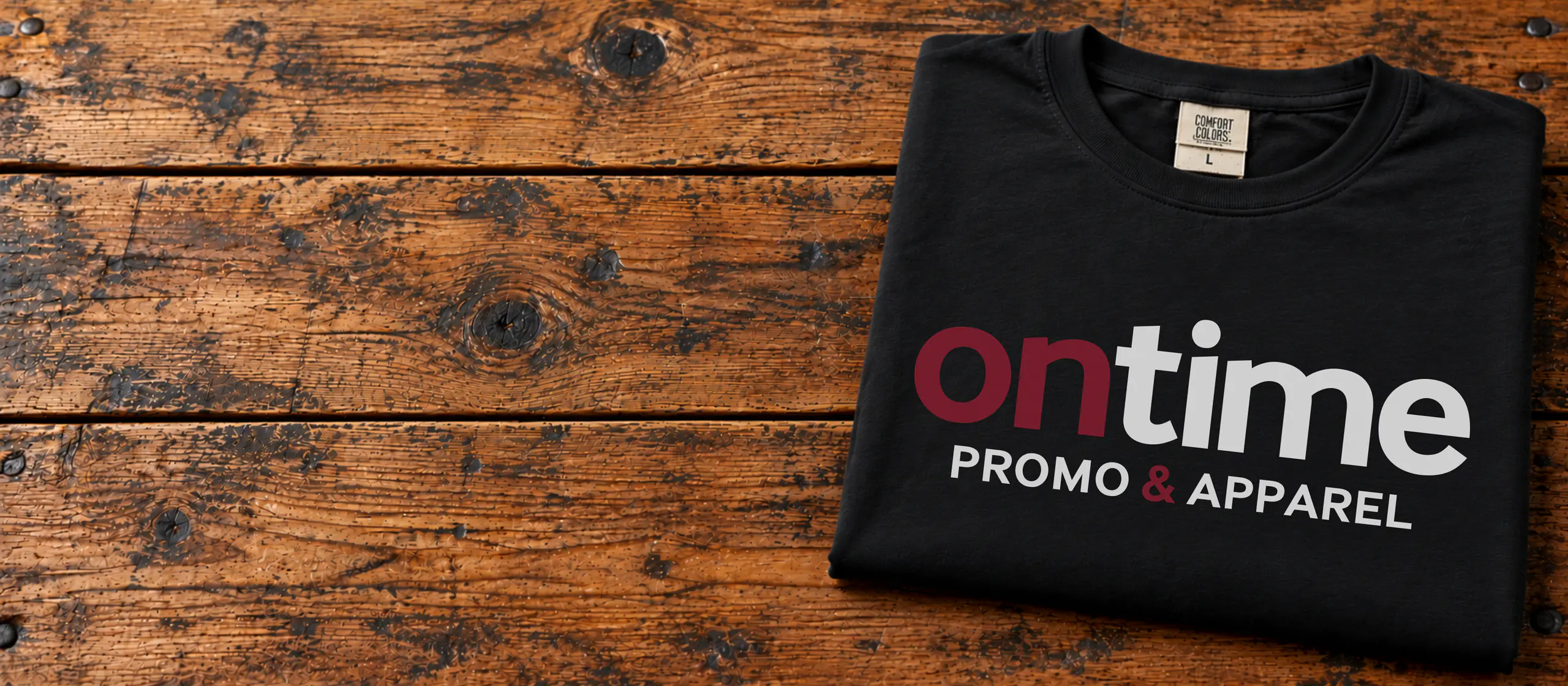 Black OnTime Promo & Apparel logo t-shirt folded on a wooden table
