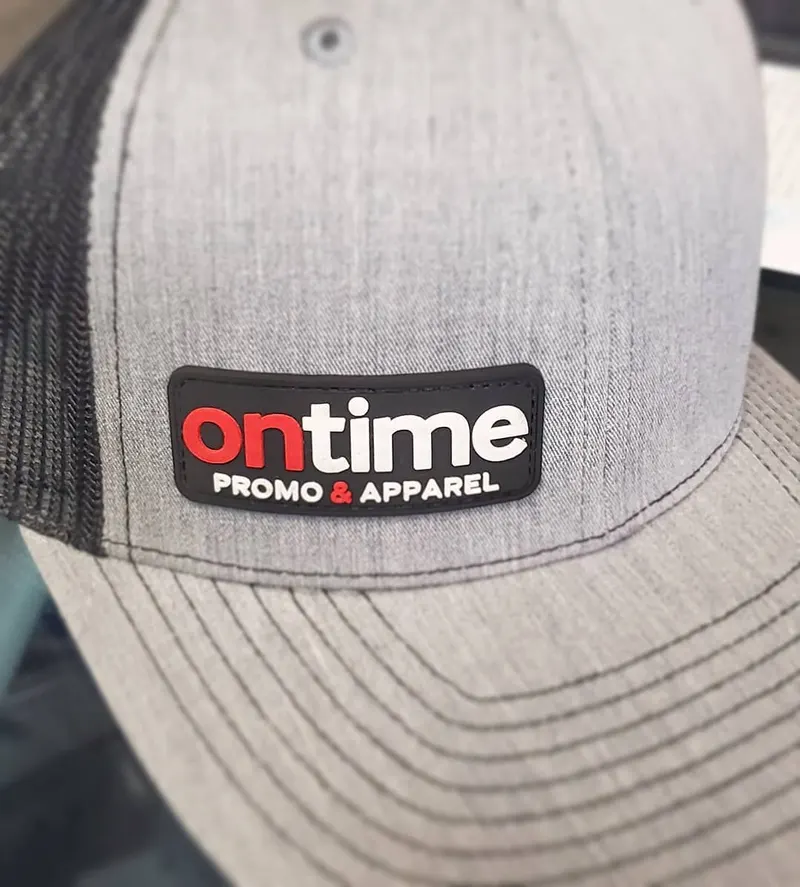 Gray trucker hat with a custom OnTime Promo & Apparel logo patch